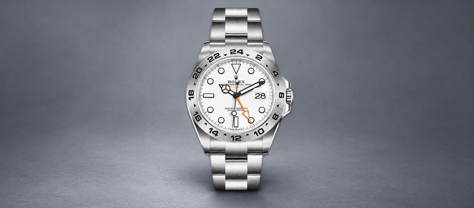 Rolex Explorer II 226570 with white dial, orange 24-hour hand, engraved steel bezel and Oyster bracelet on a slate-gray background