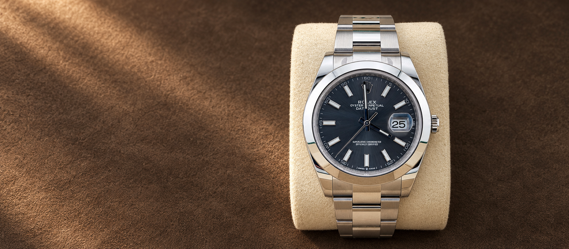 Rolex Datejust 41 reference 126300 with slate dial, smooth bezel and steel Oyster bracelet on a cream cushion against a warm brown suede background.