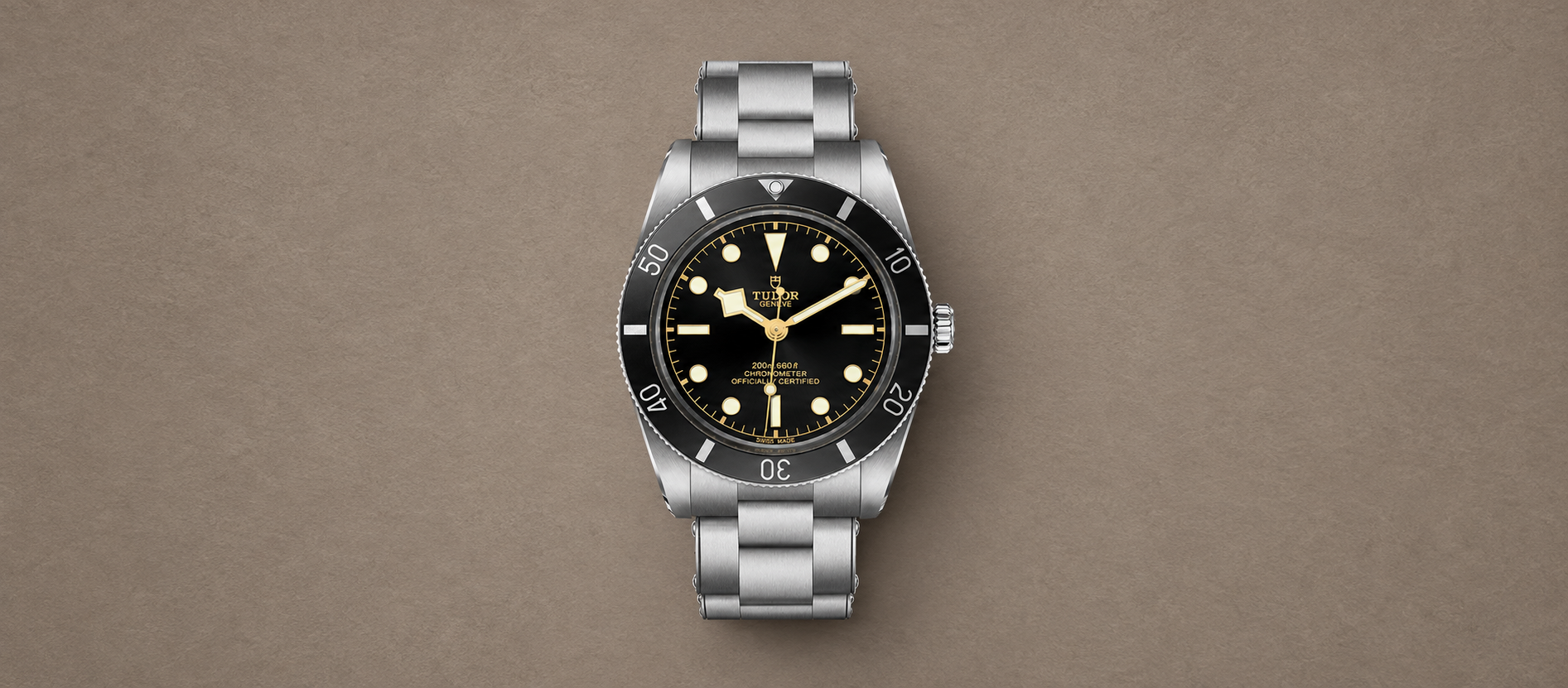 Tudor Black Bay 54 M79000N-0001 with black dial and steel bracelet against a warm taupe background