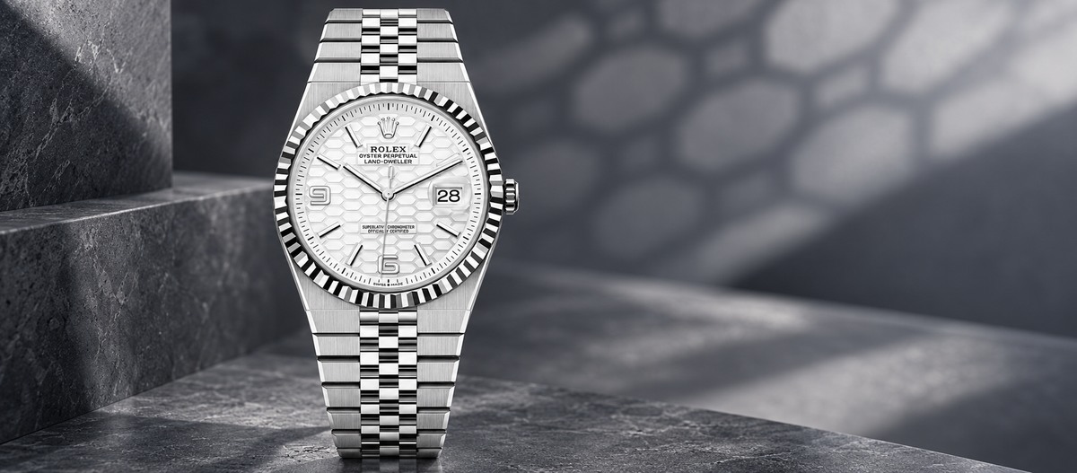 Rolex Land-Dweller 40 reference 127334 with white honeycomb dial, fluted bezel and Flat Jubilee bracelet on a charcoal stone background